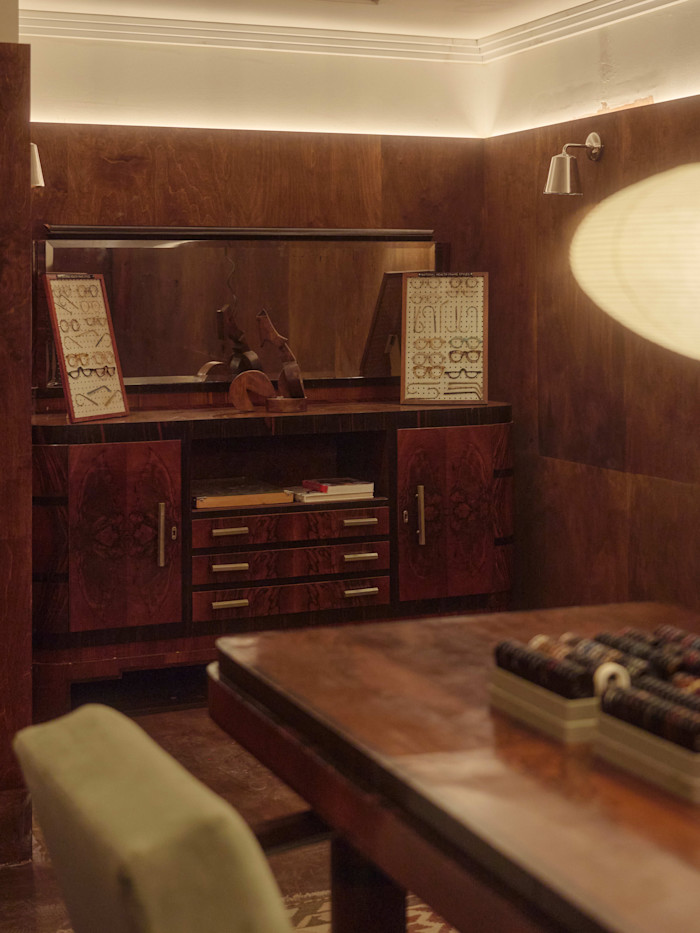 A wooden cupboard on which glasses are displayed, in a wood-panelled room.