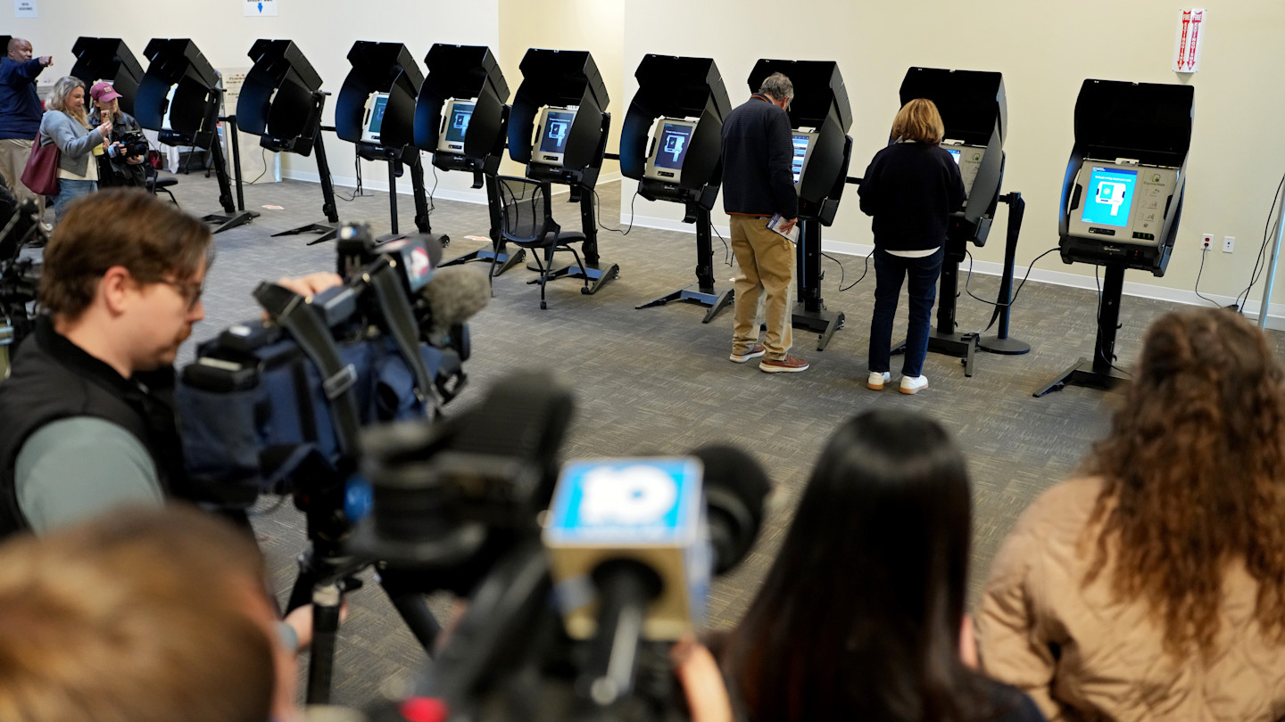 Sherrod Brown and his wife Connie Schultz use electronic voting machines as members of the media film them at a polling place in Columbus, Ohio