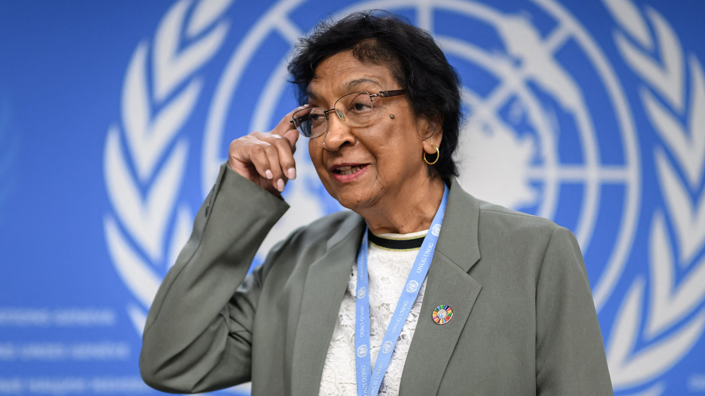 Navi Pillay gestures as she arrives at a press conference, standing in front of a United Nations backdrop.