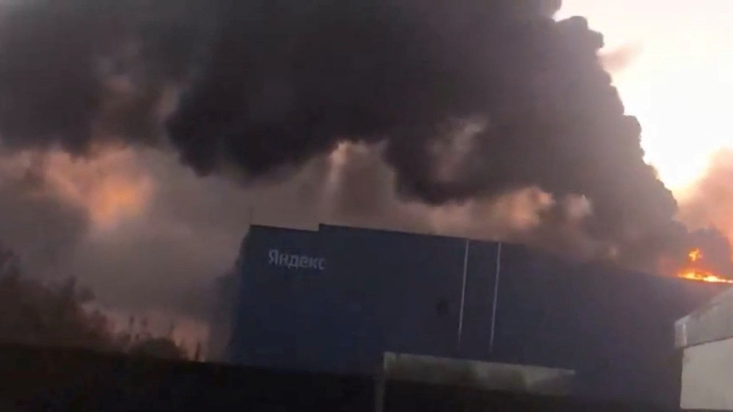 Thick black smoke rises from the roof of a Yandex data centre building as flames are visible behind the structure.