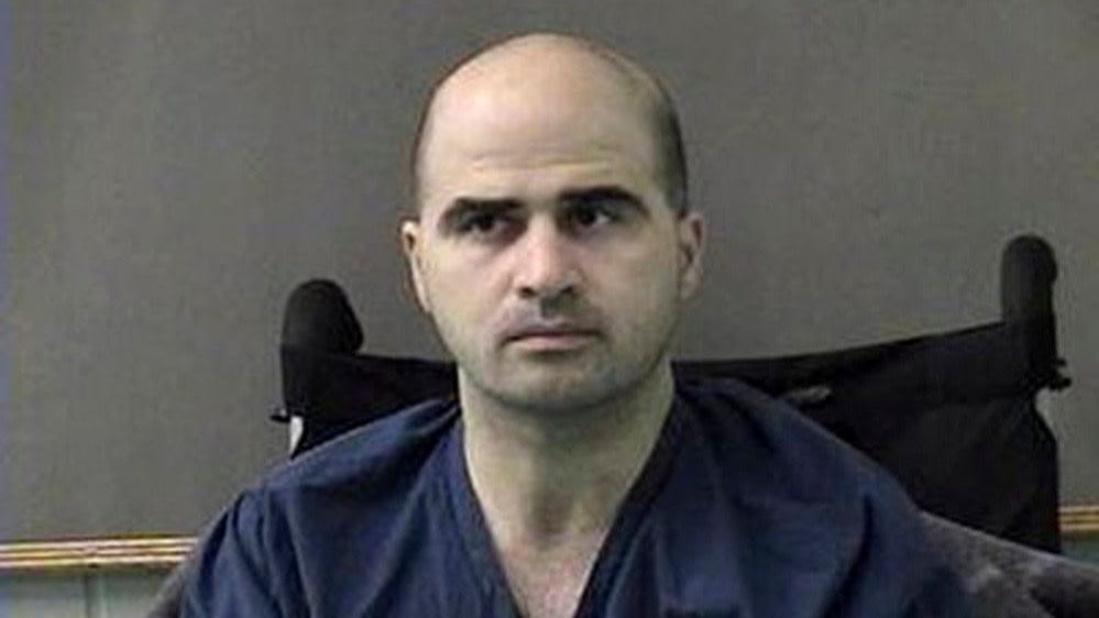 Nidal Hasan seated and wearing a blue shirt