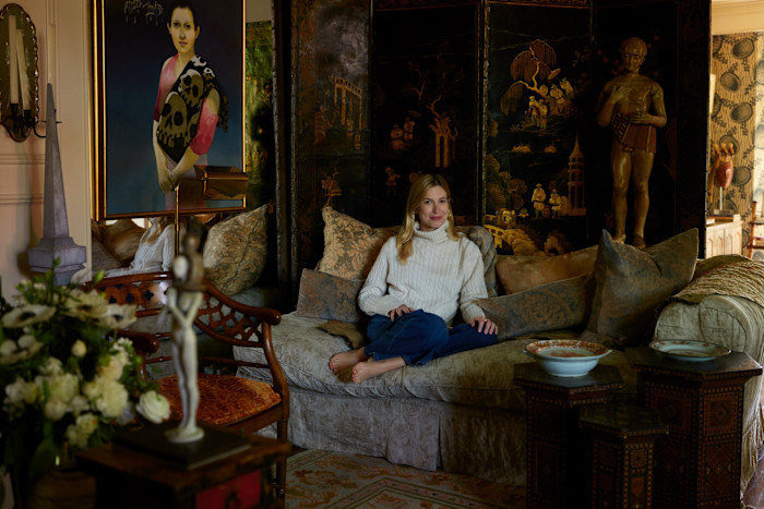 Raymond’s granddaughter Kate Klausner in the living room; on the mirrored wall is a 1996 painting by Morris Broderson beside a 19th-century Japanese screen