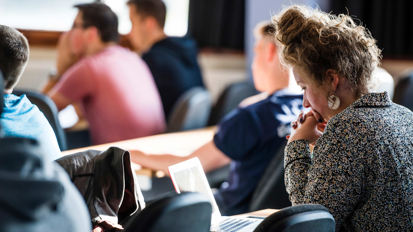 Students at Aberystwyth University sit in a lecture hall, using laptop computers during class.