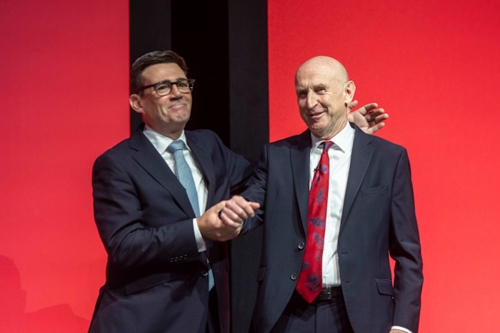 Chancellor John Healey and Prime Minister Andy Burnham smiling and clasping hands on stage after Healey’s keynote speech.