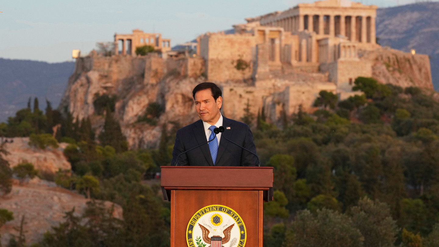 U.S. Secretary of State Marco Rubio speaks at a podium outdoors, with the ancient Parthenon atop the Acropolis visible in the background.