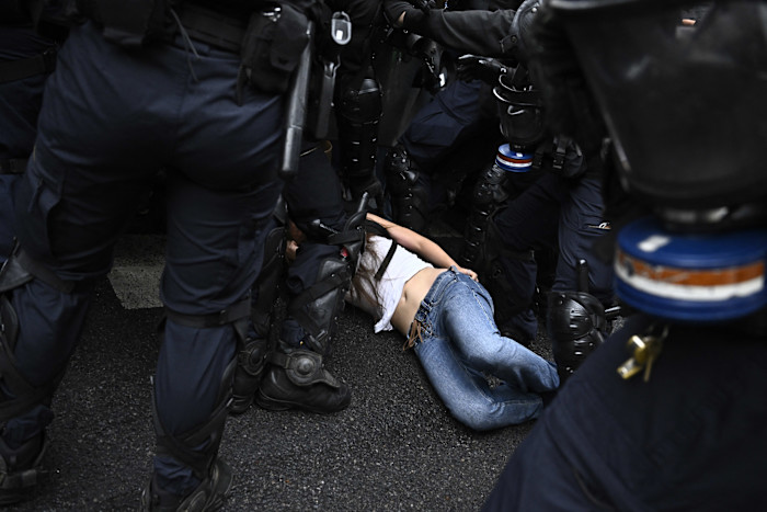 A protester lies on the ground surrounded by French riot police during a demonstration in Paris.