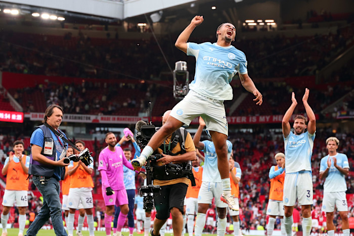 Iliman Ndiaye of Manchester City jumps and celebrates as teammates applaud after the team's 1-0 win over Manchester United.