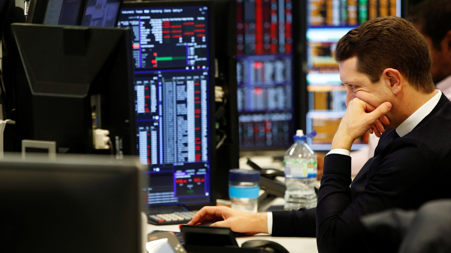 A trader sits at a desk focused on several computer monitors displaying market data at CMC Markets.