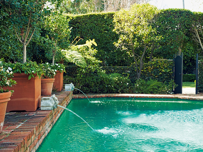 Stone lion-head corbel fountains by the pool