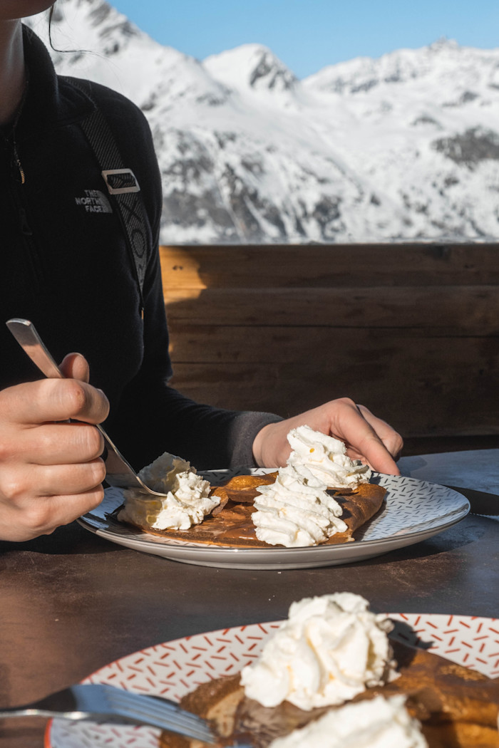 Pancakes with cream on a wooden table with a view of mountains behind