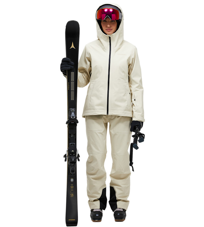 A model wearing a cream ski jacket and trousers with pink-tinted goggles.