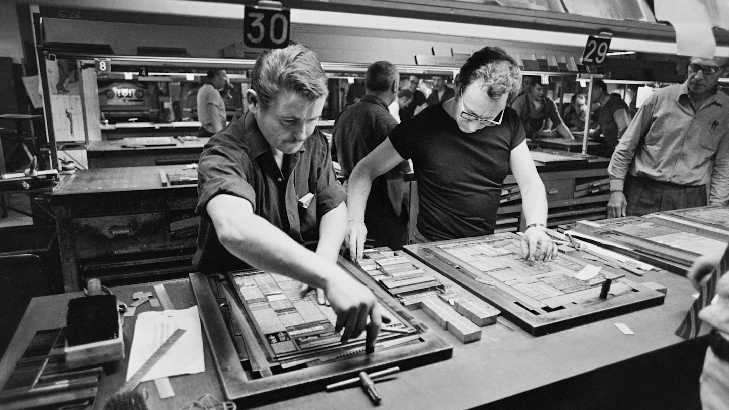 Workers assembling newspaper pages at large tables in the Le Monde press room, Paris, in 1970.