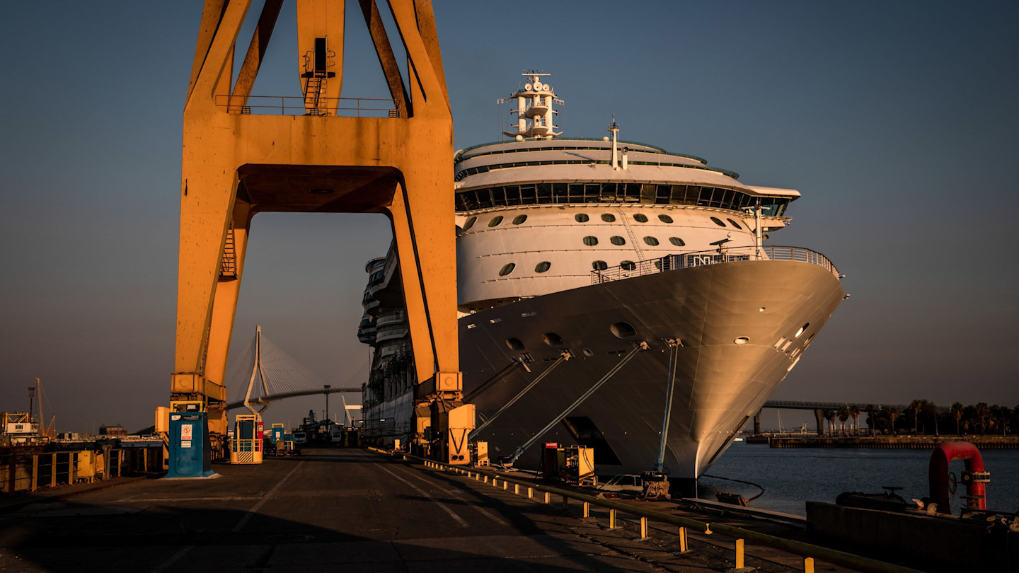 Radiance of the Seas cruise ship docked at a shipyard, with a large yellow crane in the foreground.