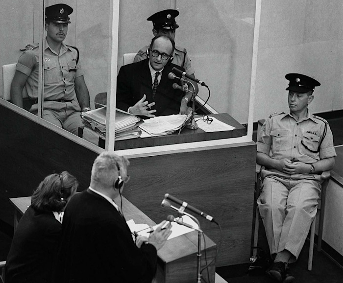 Adolf Eichmann sits in a glass booth flanked by Israeli police during his 1961 trial in Jerusalem.