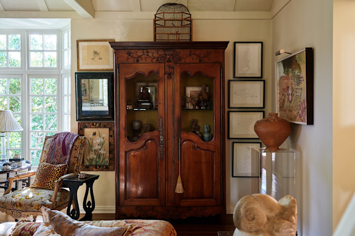 In the living room is a Louis XV armoire with a French oak birdcage on top of it