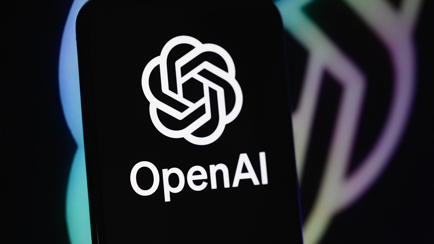 The OpenAI logo and name displayed on a smartphone screen with a blurred background in dark colours