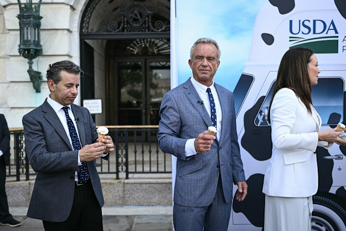 Robert F Kennedy Jr holds an ice-cream cone while standing next to an ice-cream van
