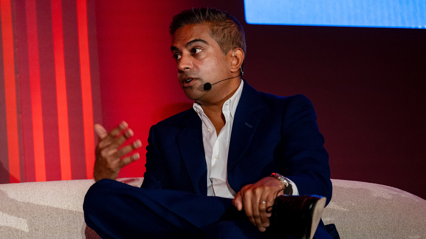 Dipan Patel speaks while seated on stage, wearing a dark suit and headset microphone at the FT Private Capital summit.