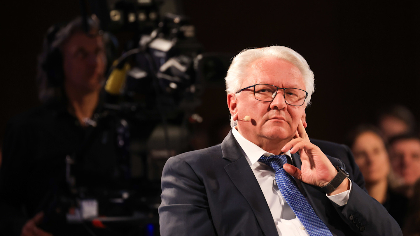Armin Papperger sits wearing a suit and tie, with a headset microphone, appearing thoughtful during the Berlin Global Dialogue.