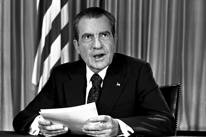 President Richard Nixon sits at a desk in his White House office holding papers after delivering a television address on Watergate.
