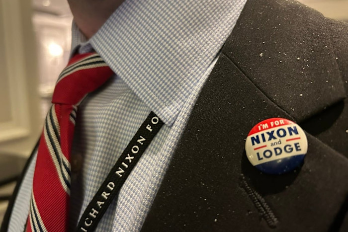 A delegate at the Grand Strategy Summit wears a “Nixon and Lodge” campaign button on a suit, along with a Richard Nixon Foundation lanyard.