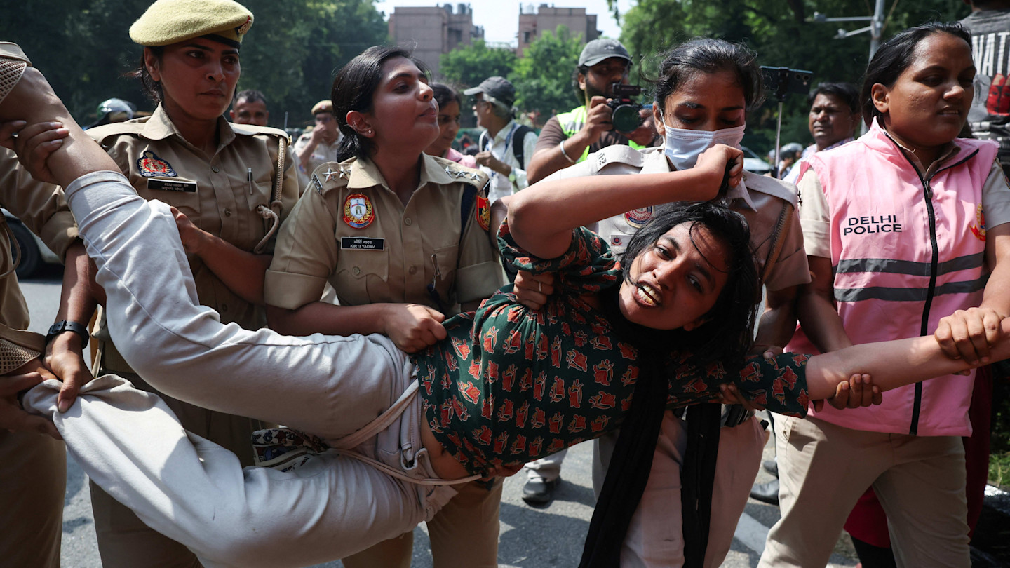 A protester is carried and detained by several Delhi Police officers during a demonstration