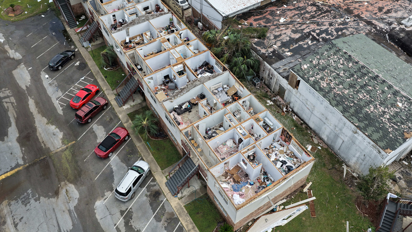 Aerial view of an apartment complex in Florida with the roof torn off, exposing damaged and debris-filled rooms after Hurricane Isaias