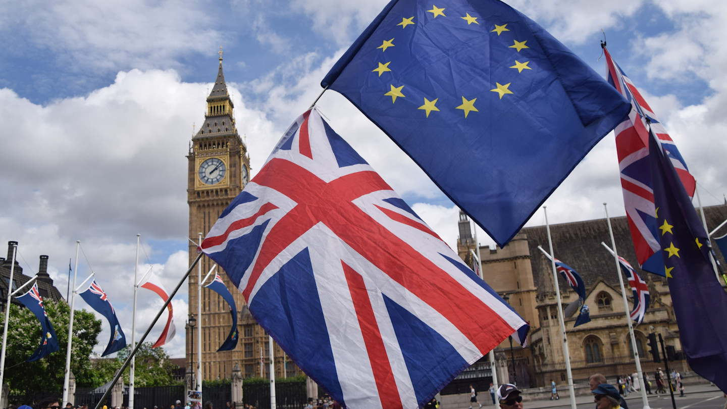 Union Jack and EU flags held aloft in front of Big Ben during a protest in Parliament Square