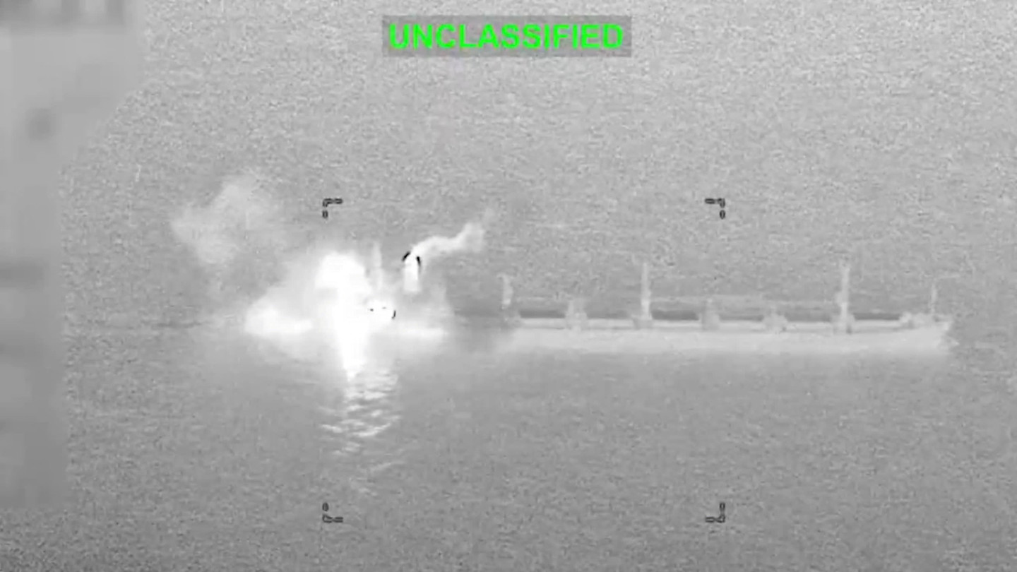 Smoke and flames burst from a cargo ship at sea at night following a strike, seen in a grainy infrared image marked ‘unclassified’