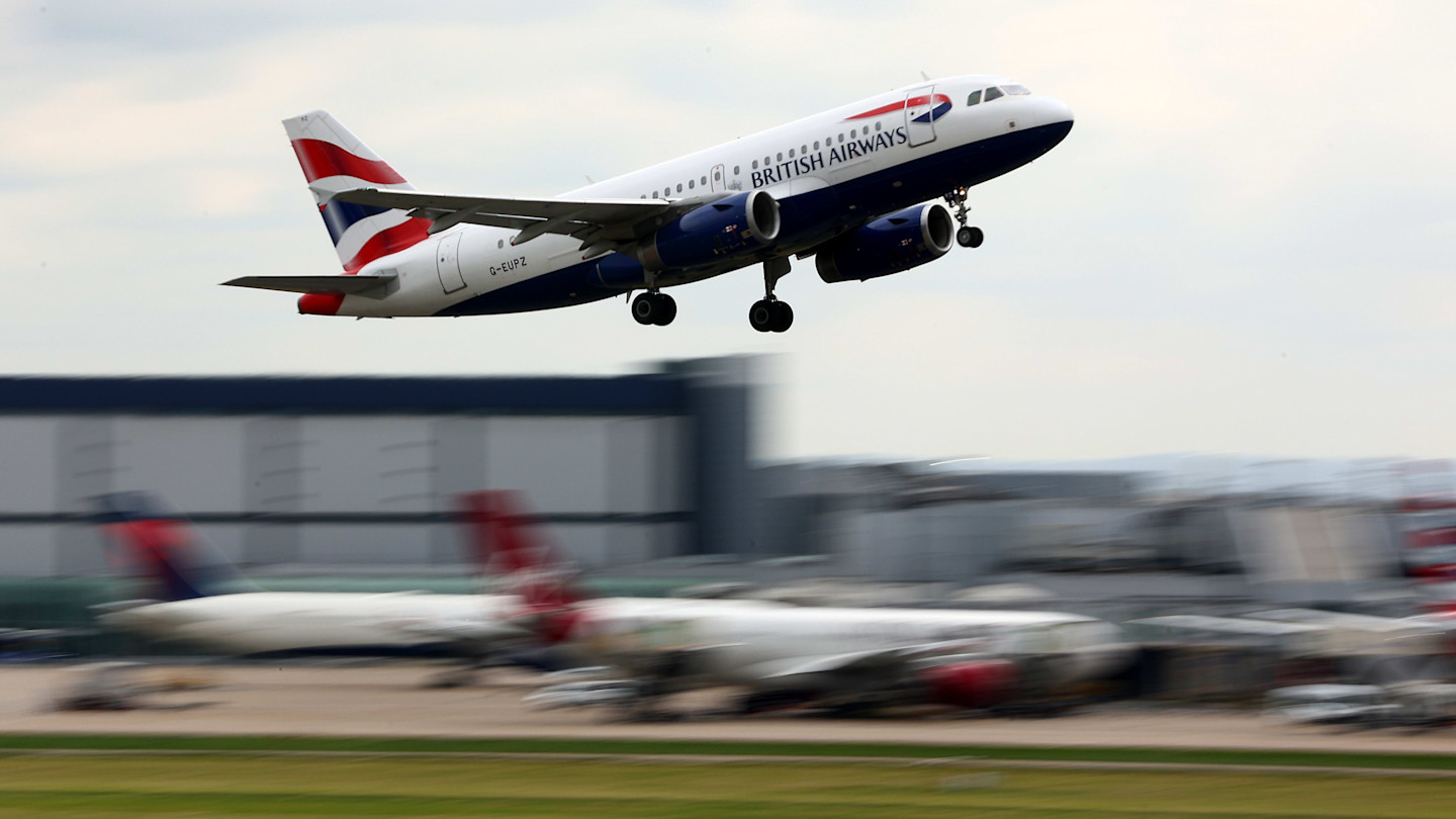 A British Airways Airbus A319 ascending after take-off from Heathrow airport, with other planes and airport buildings in the background.