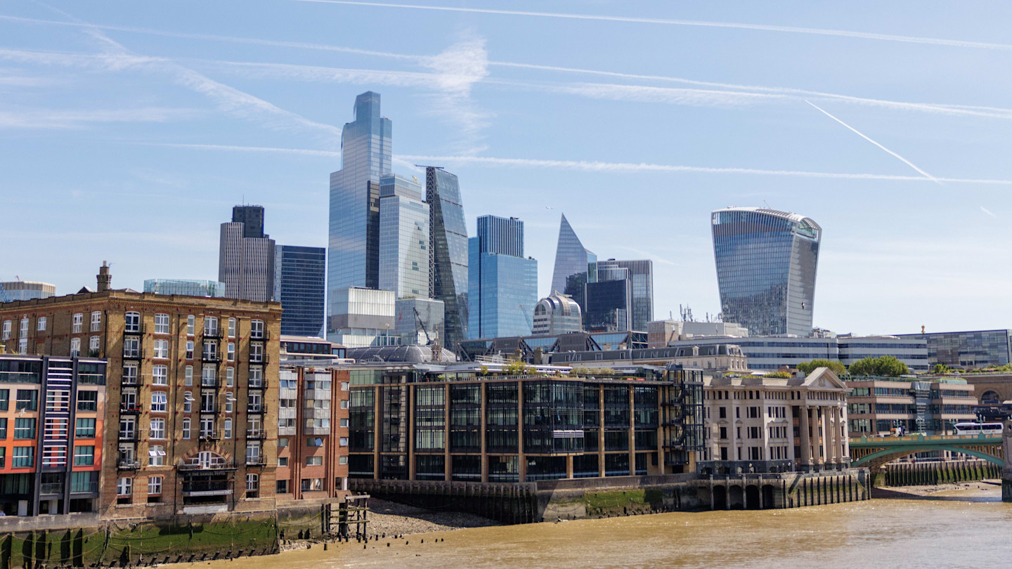 Skyscrapers and modern office buildings in the City of London financial district with the River Thames in the foreground.