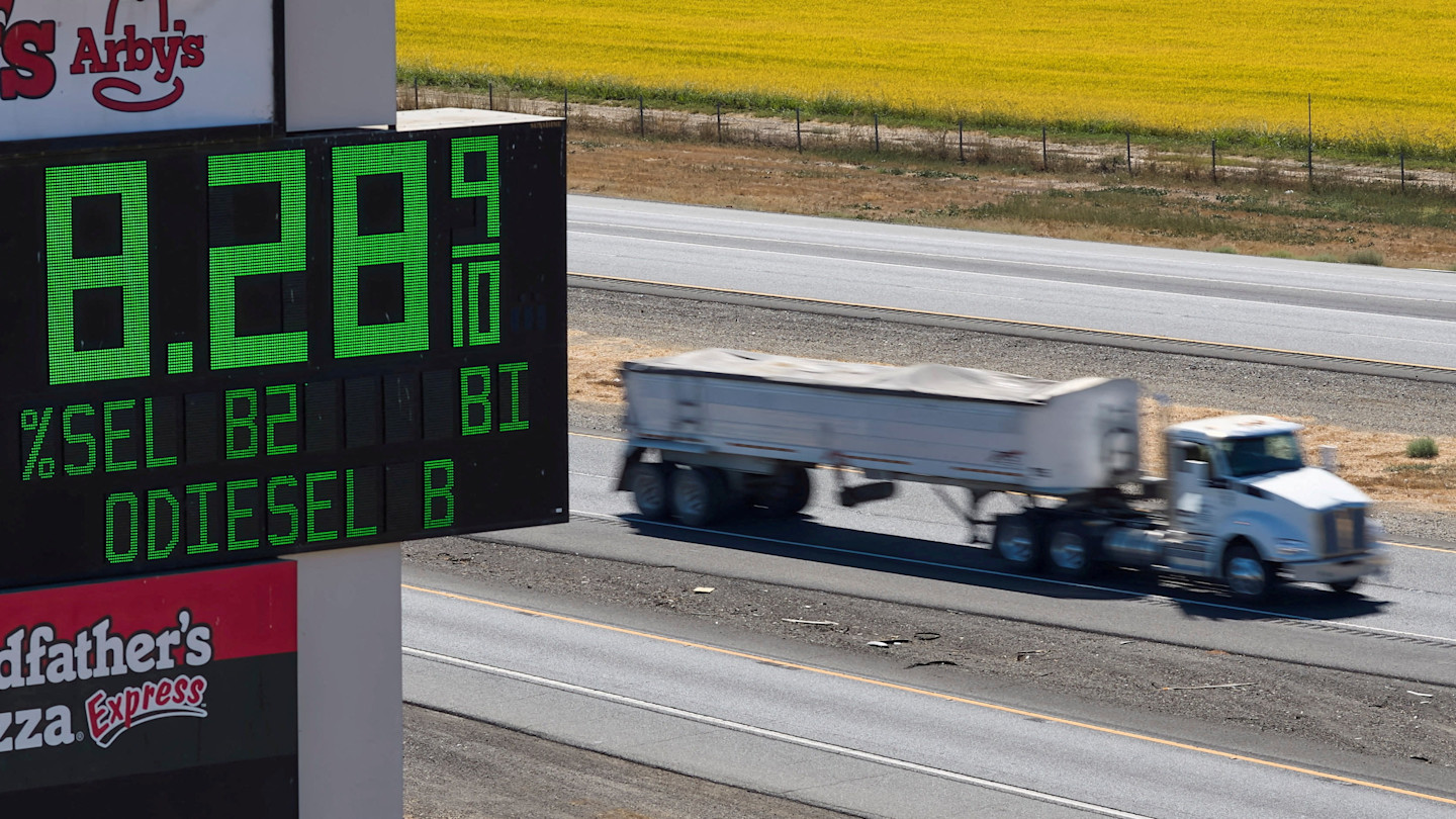 A large electronic sign displays diesel at $8.28 per gallon as a truck drives past on the highway.