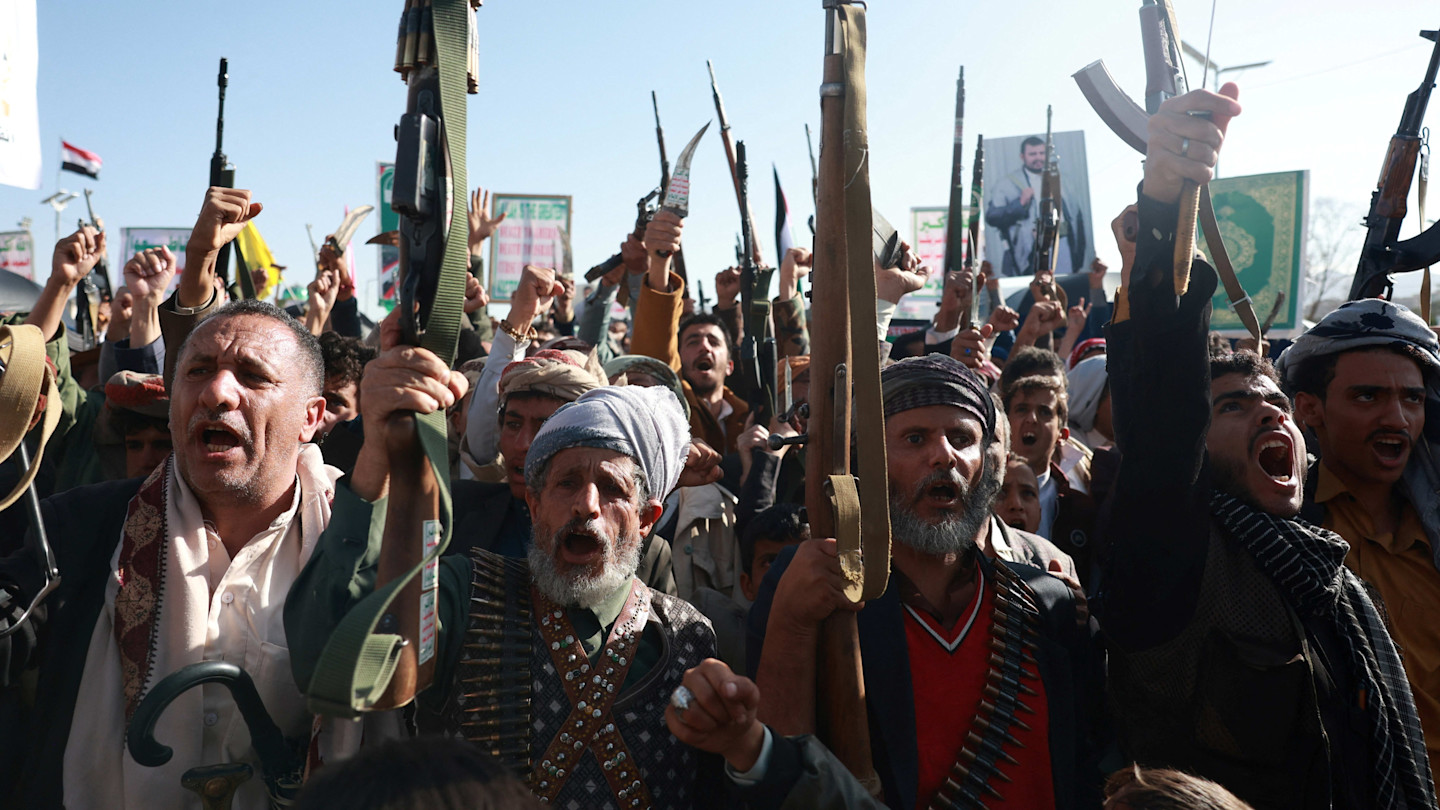 A crowd of Houthi supporters, many armed and shouting, raise rifles and fists during a rally in Sanaa, Yemen.