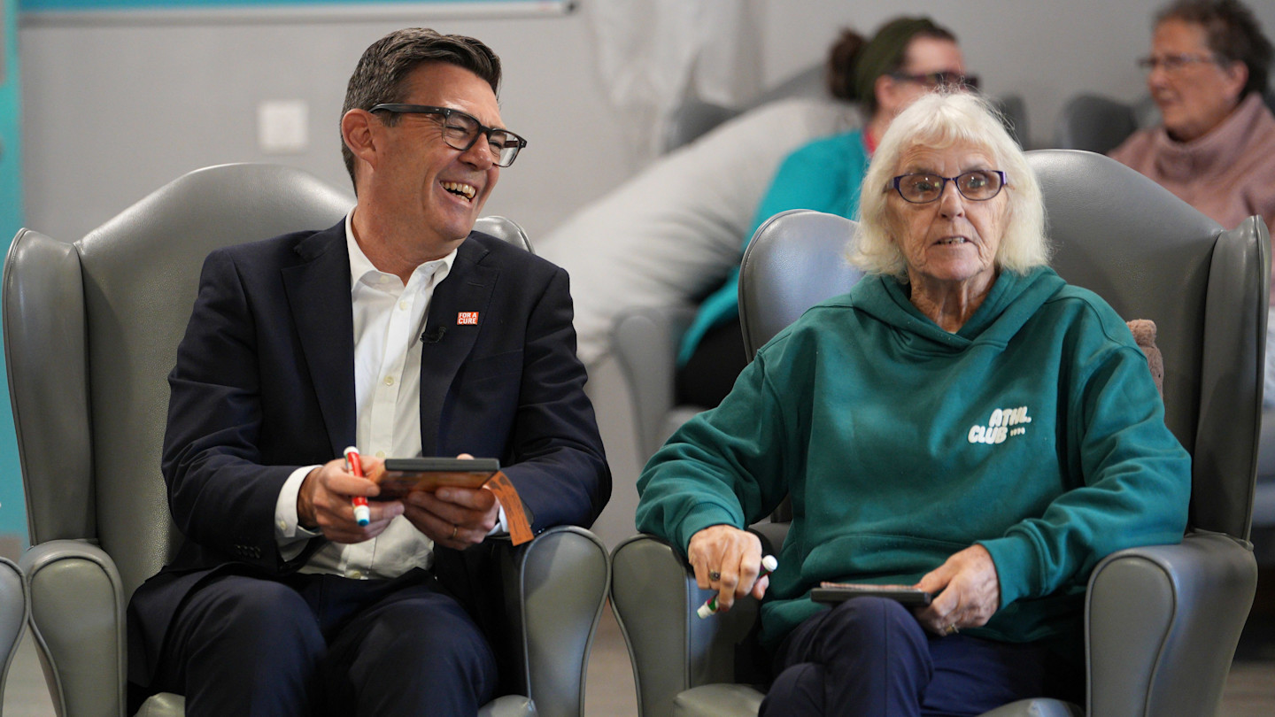 Andy Burnham smiles while playing bingo with Brenda Fiocociello, who holds a bingo marker, at the resource centre.