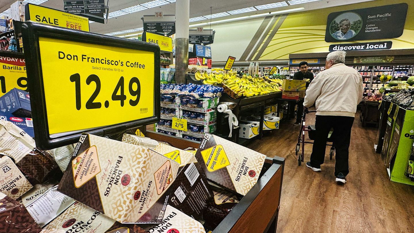 Coffee priced at $12.49 is displayed on a prominent yellow sign above Don Francisco’s Coffee boxes in a supermarket aisle.