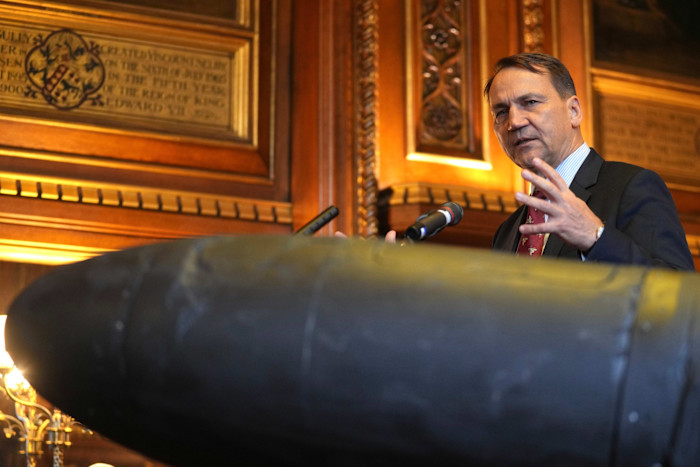 Radosław Sikorski speaks at a podium next to a Shahed-136 attack drone during a press conference in parliament.