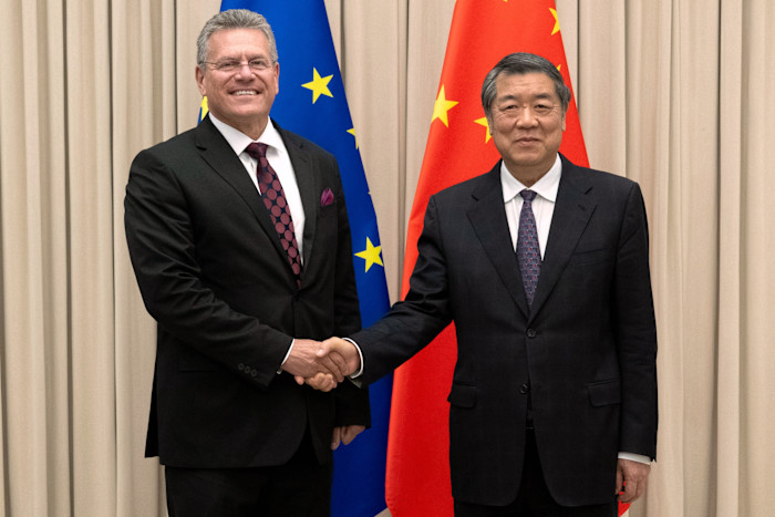 He Lifeng shakes hands with Maroš Šefčovič in front of the European Union and Chinese flags before their meeting