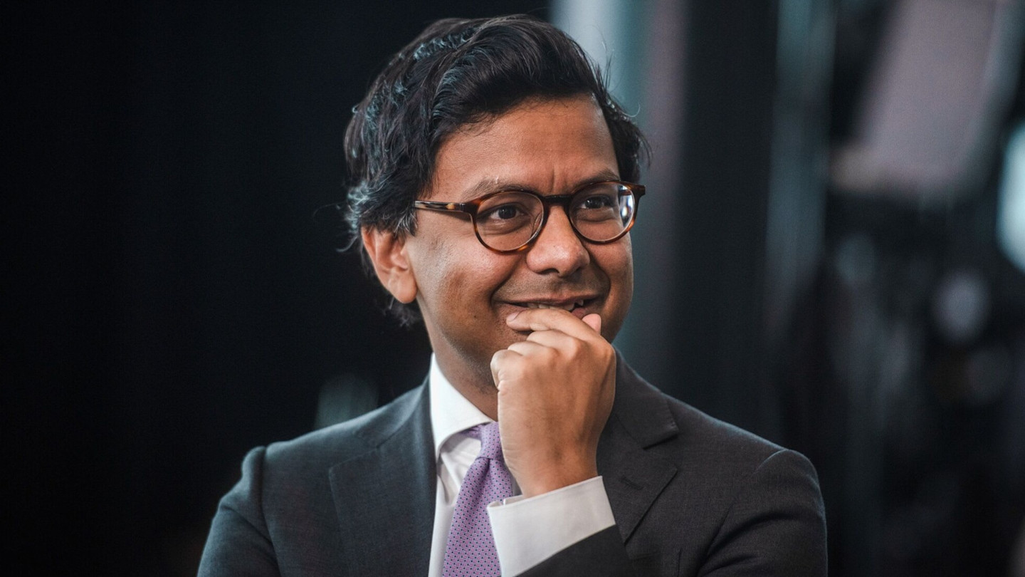 Kanishka Narayan smiling and resting his chin on his hand during a television interview.