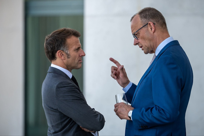 Friedrich Merz gestures while speaking with Emmanuel Macron.