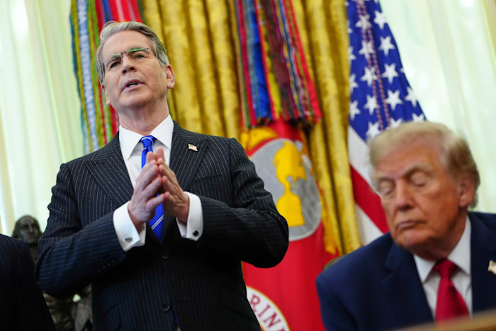Scott Bessent speaks with hands clasped as President Donald Trump listens beside him in the Oval Office.