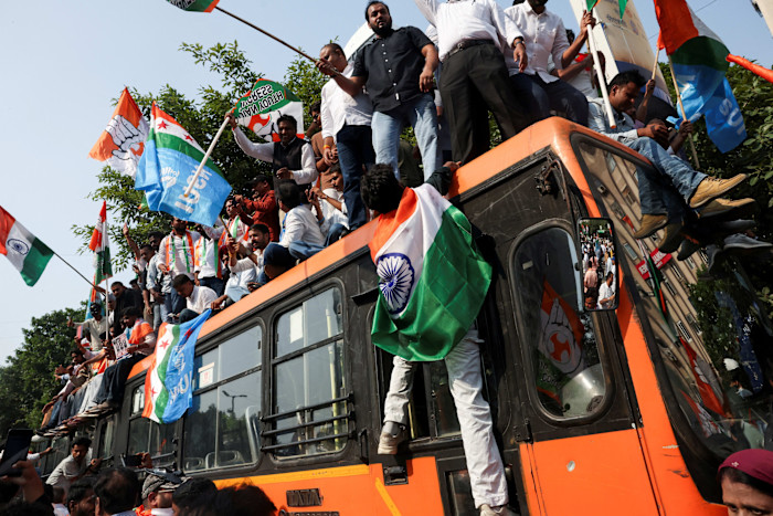 Opposition supporters climb on a bus with placards and flags to protest against a controversial voter list revision in New Delhi on Monday
