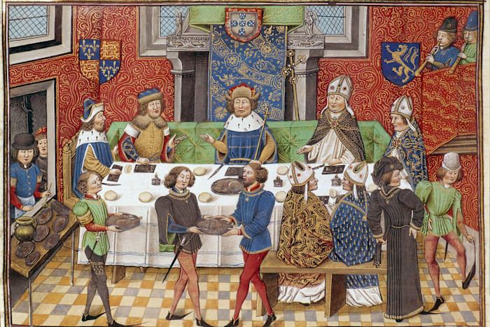 An illustration showing John of Gaunt and John I of Portugal seated at a banquet table, attended by courtiers and clergy.
