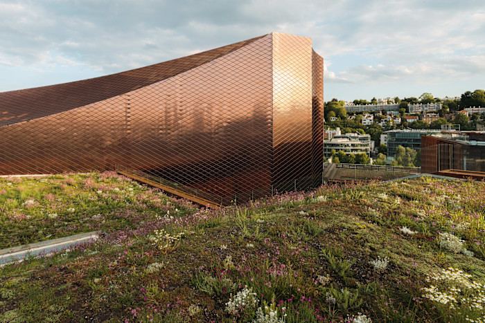 A side view of a large modern building with a bronze-coloured facade.