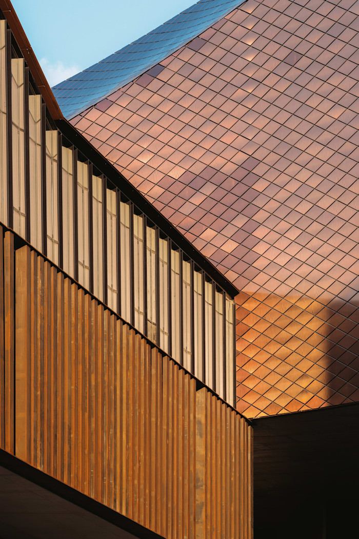 A close-up of a large modern building clad in diamonds of copper-coloured metal.