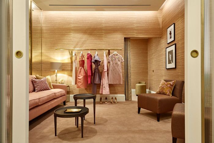 Items of clothing hang on a rail in a room where there are armchairs and coffee tables.