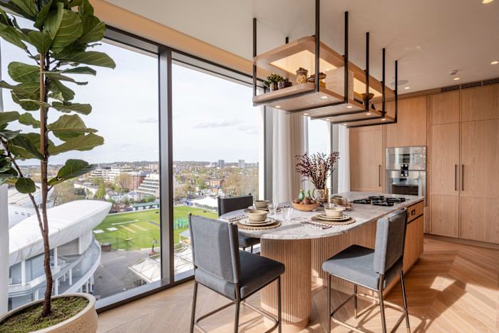 A modern dining room with floor-to-ceiling windows overlooking a green landscape.
