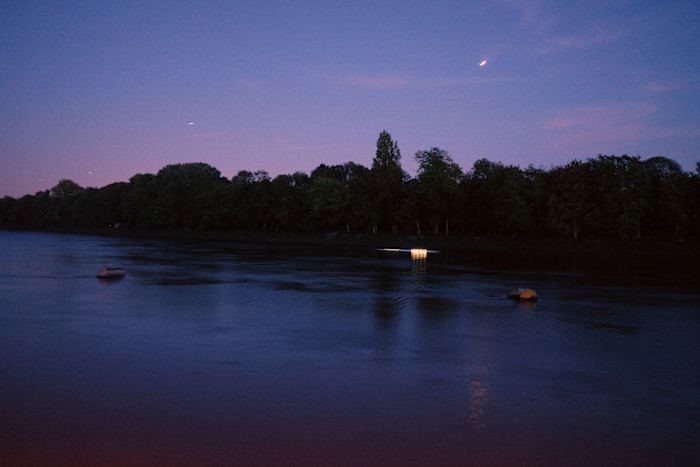 A view of the Thames at dusk, with trees lining the opposite bank.