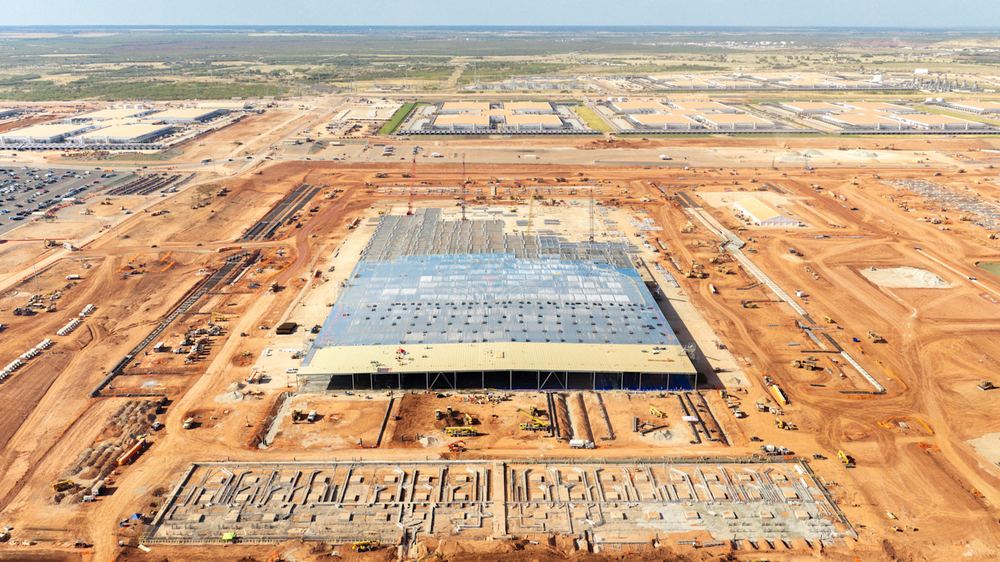 Aerial view of the Stargate Oracle AI data centre under construction, showing a large building surrounded by construction equipment and red dirt.