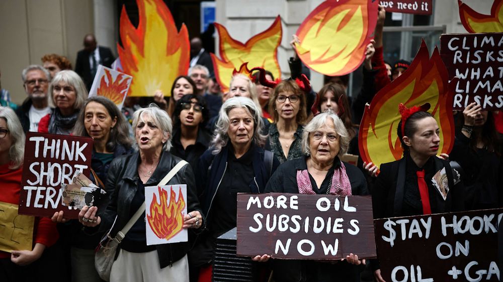 Protesters hold placards with slogans and drawings of flames, some wearing red devil horns, at a demonstration against North Sea oilfields.