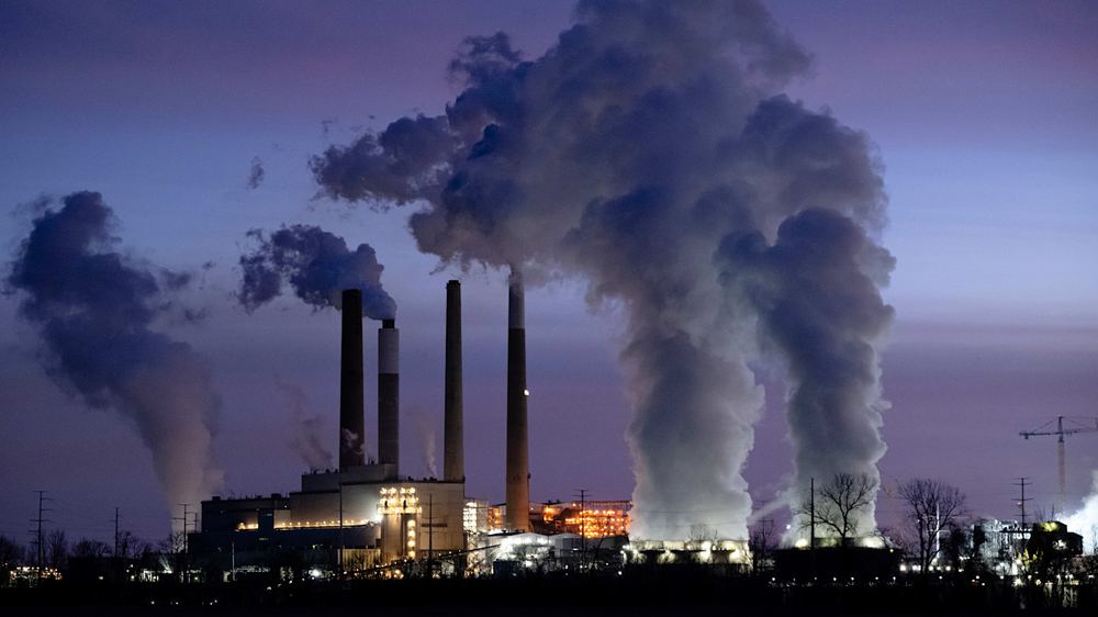 Thick plumes of smoke rise from multiple smokestacks at the Mill Creek Generating Station, a coal-fired power plant, at dusk.
